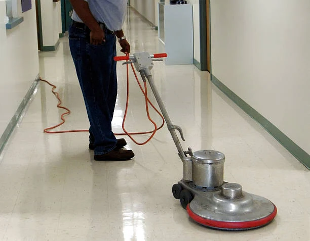 A person expertly operates a floor buffer as part of building maintenance, making the shiny tiled hallway glisten with pristine perfection, Commercial Cleaning